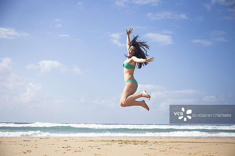 在西班牙富埃特文图拉岛海滩上跳跃欢笑的女人图片素材