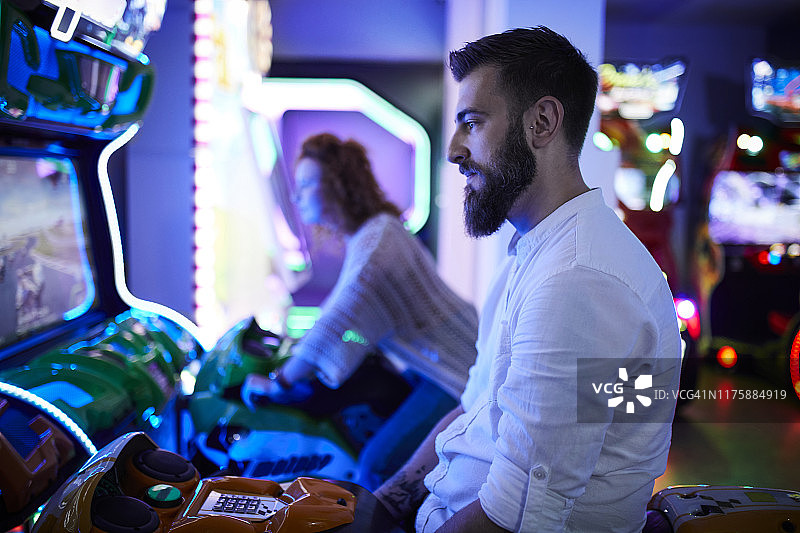 在游乐厅驾驶模拟器上的男人图片素材