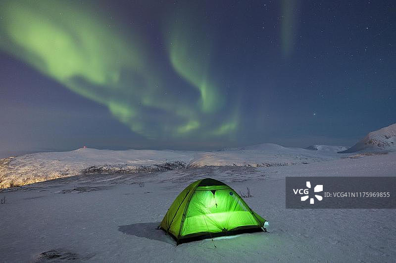挪威特罗姆瑟，菲尔海森山上被极光照亮的绿色帐篷图片素材
