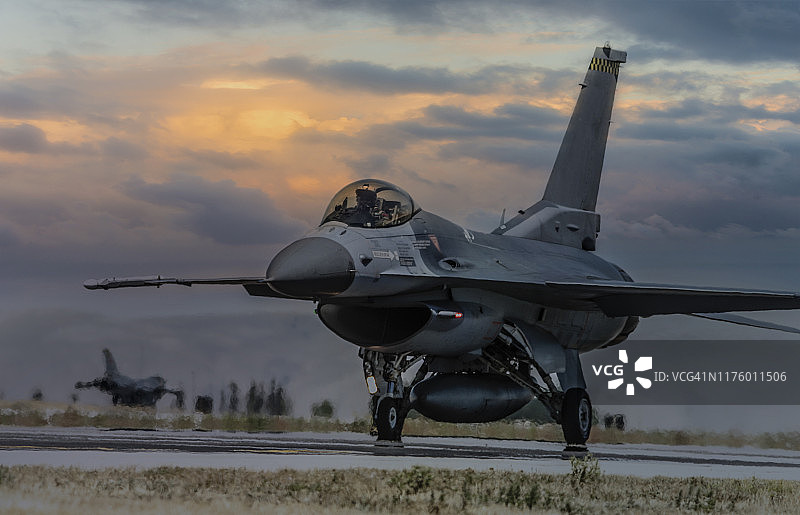 日落时分准备在跑道上起飞的F-16战斗机图片素材