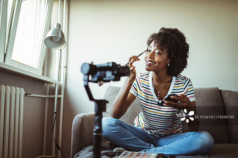 漂亮的非裔美国女人美妆视频博主录制化妆教程图片素材