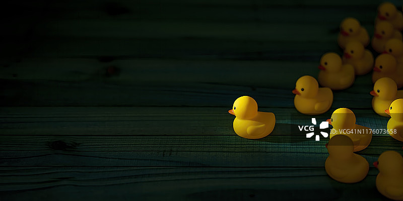一群黄色橡胶鸭跟随领头鸭，驶向光芒图片素材