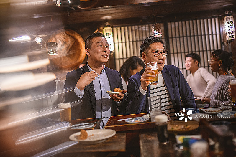 日本男人在居酒屋享用啤酒和食物图片素材