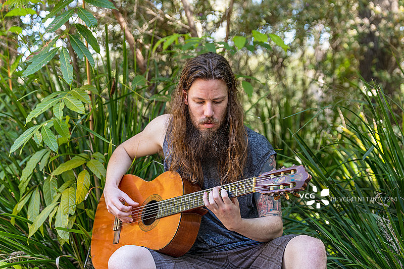 在公园里弹吉他的长发男人图片素材