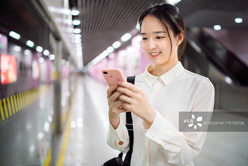 年轻亚裔女性在地铁站使用智能手机图片素材