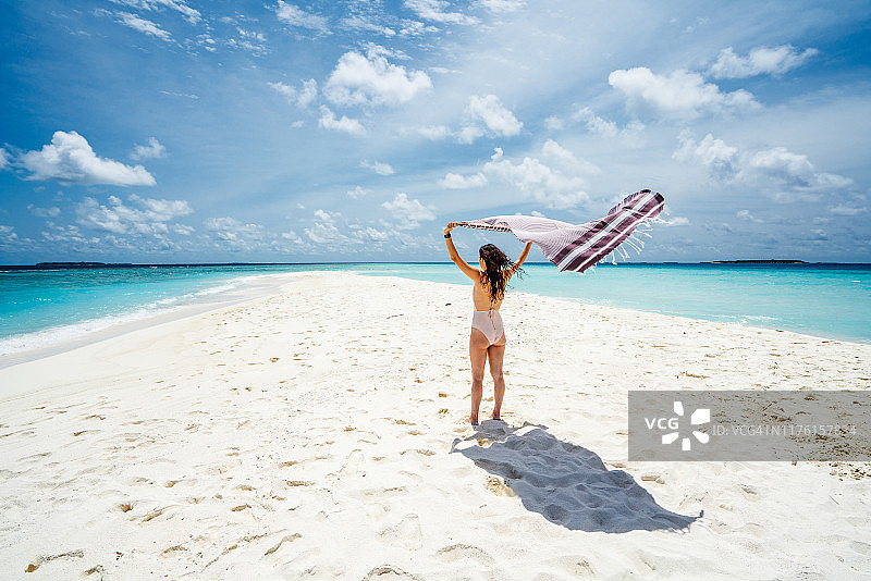 在马尔代夫天堂般的海滩上享受的年轻女人图片素材