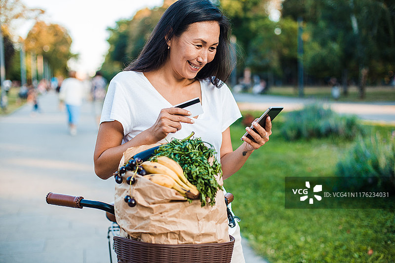 骑着自行车、提着购物袋的女人在线购物图片素材