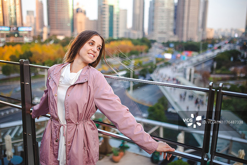 倚靠在阳台围栏上欣赏风景的迷人女性图片素材