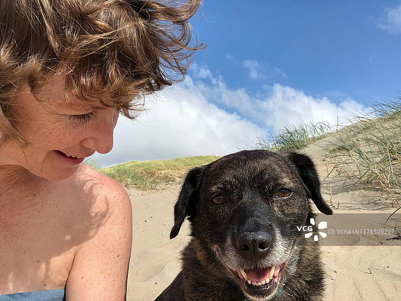 中年妇女和她的狗在海滩上图片素材