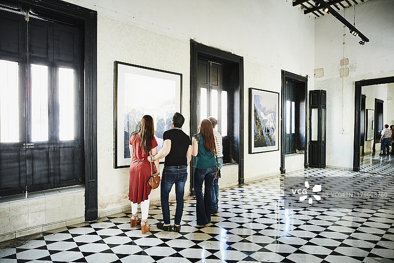 在美术馆购物时欣赏艺术品细节的两对夫妇图片素材