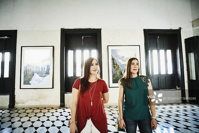 两位女性朋友在艺术画廊购物时欣赏艺术品图片素材