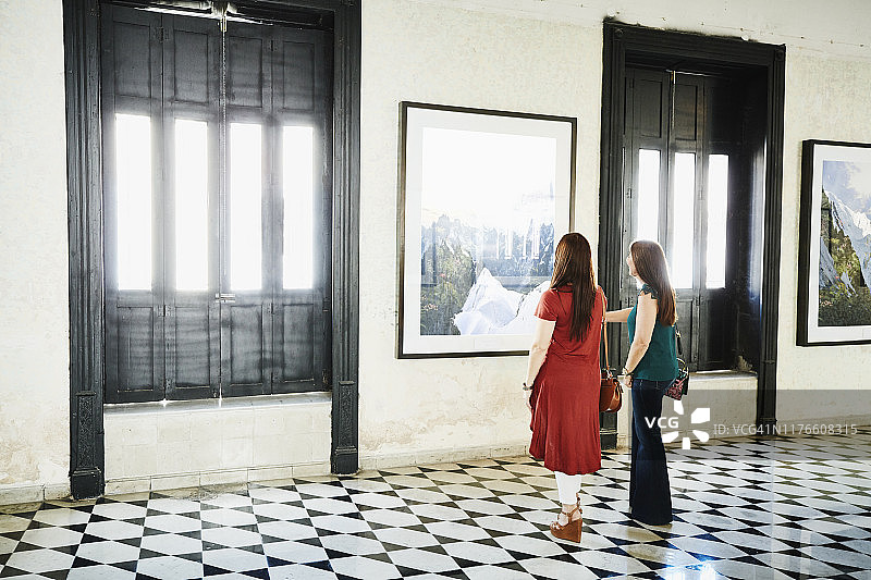 两位女性朋友在艺术馆购物时讨论艺术品细节图片素材
