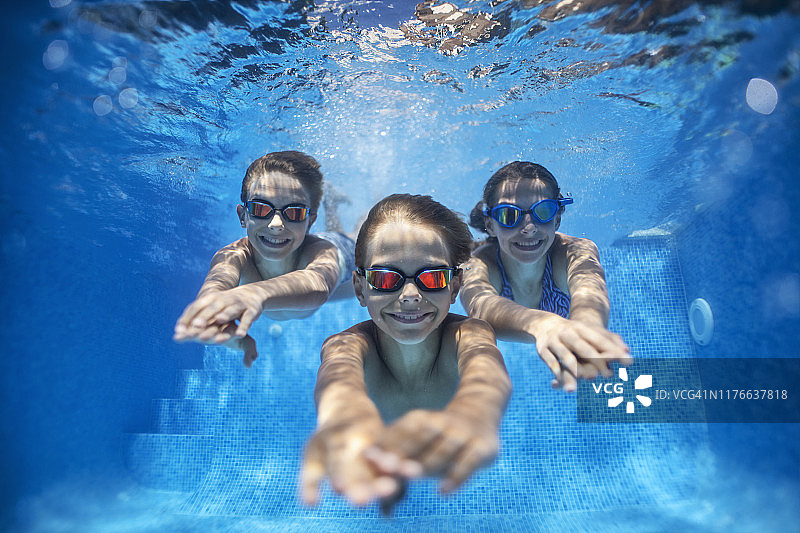 三个快乐的孩子在泳池水下游泳图片素材