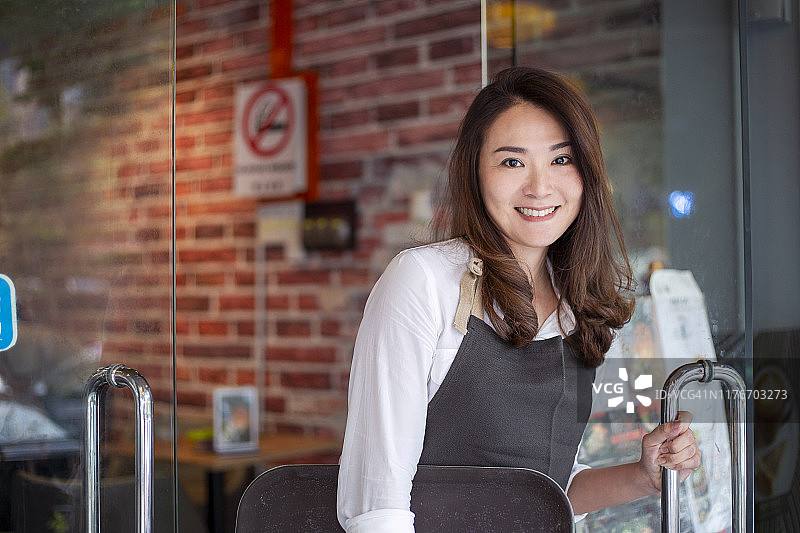 热情的咖啡馆店主在门口欢迎顾客的肖像图片素材