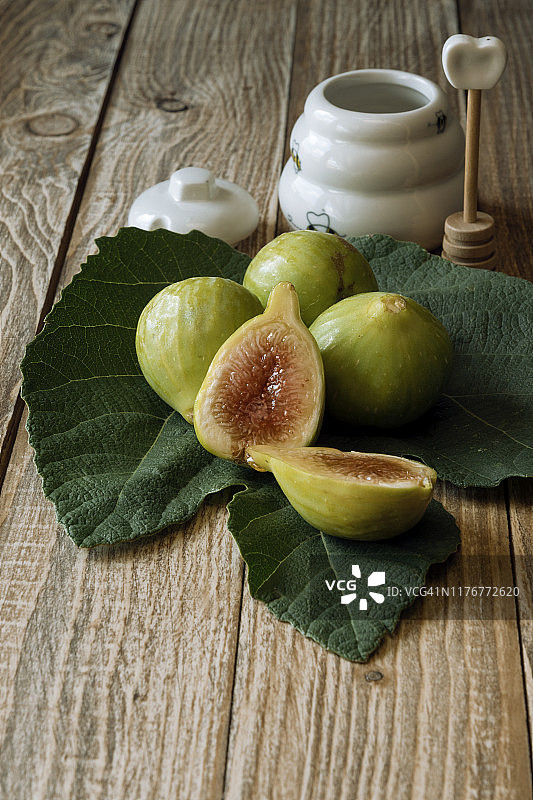 木质背景下，无花果叶和蜂蜜罐上的成熟无花果，含复制空间图片素材