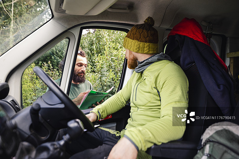 在货车里与拿着剪贴板的同事交谈的男人图片素材