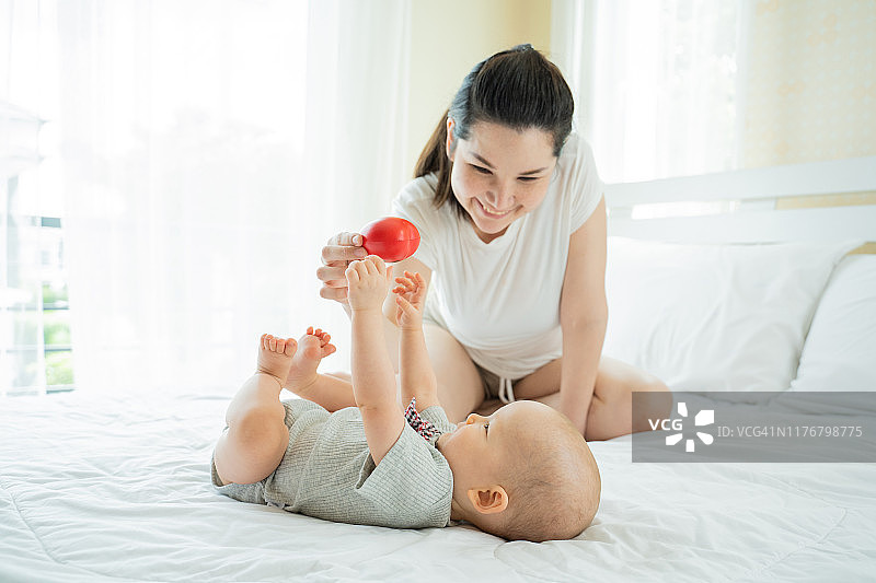 母亲和新生女婴在床上快乐地玩耍图片素材
