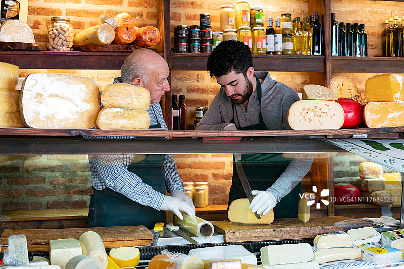 店主在熟食店监督员工摆放奶酪图片素材
