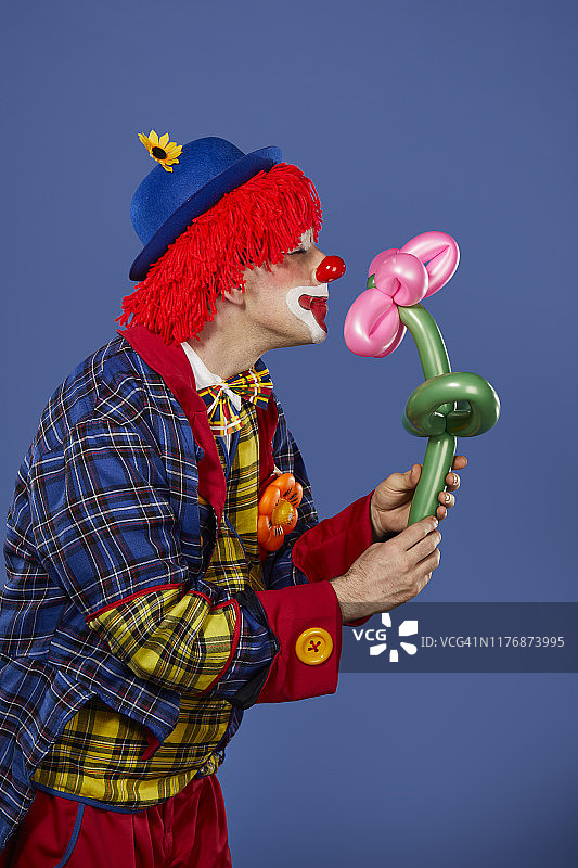 嗅着气球花的男性小丑图片素材