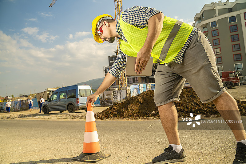 在建筑工地放置安全交通锥的建筑工人或工程师图片素材