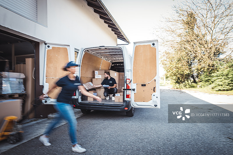 同事们赶紧将包裹装载到送货车中图片素材