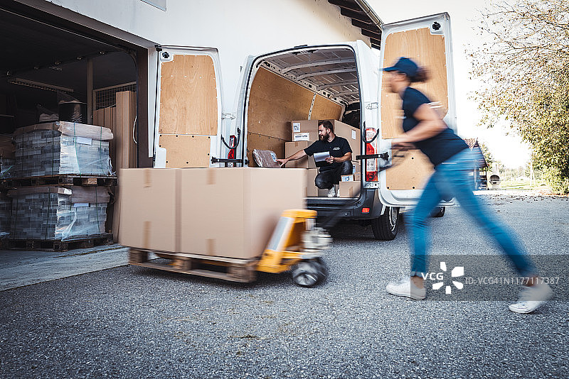 同事们赶紧将包裹装载到送货车中图片素材