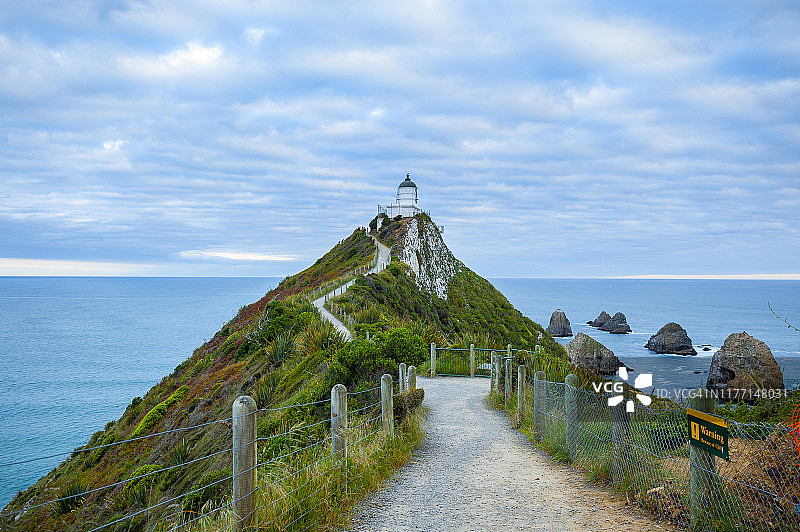 新西兰卡特林斯海岸努盖特角灯塔的路径，壮丽的景色，多云的背景和深蓝色的海洋图片素材