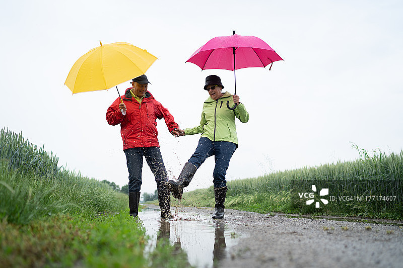 在雨天户外玩耍的快乐老年夫妇图片素材