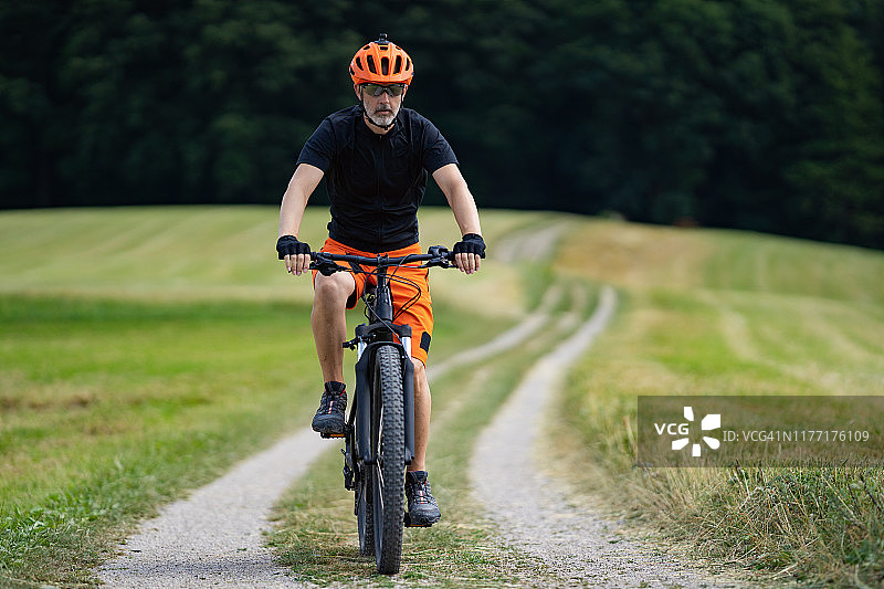 男子在乡村风景中骑电动自行车图片素材