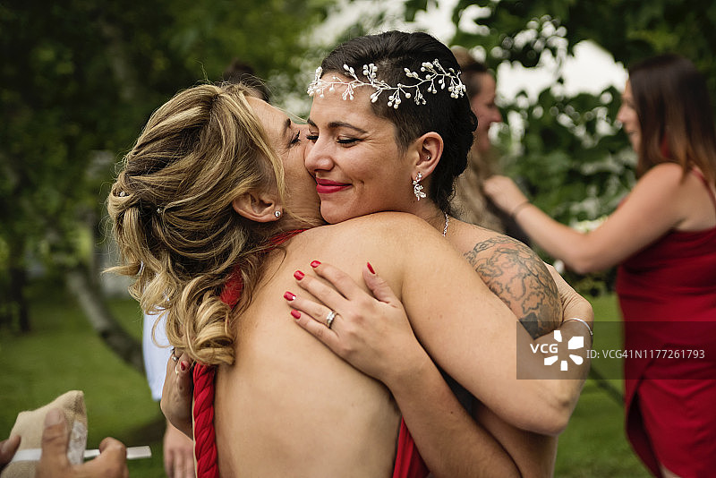 户外婚礼后拥抱母亲的千禧一代新娘图片素材