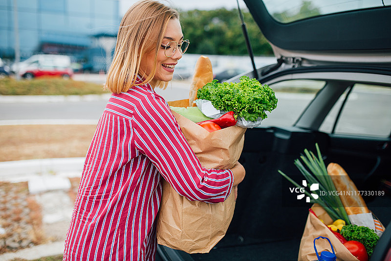 将食品杂货装进汽车后备箱的美丽年轻女人图片素材