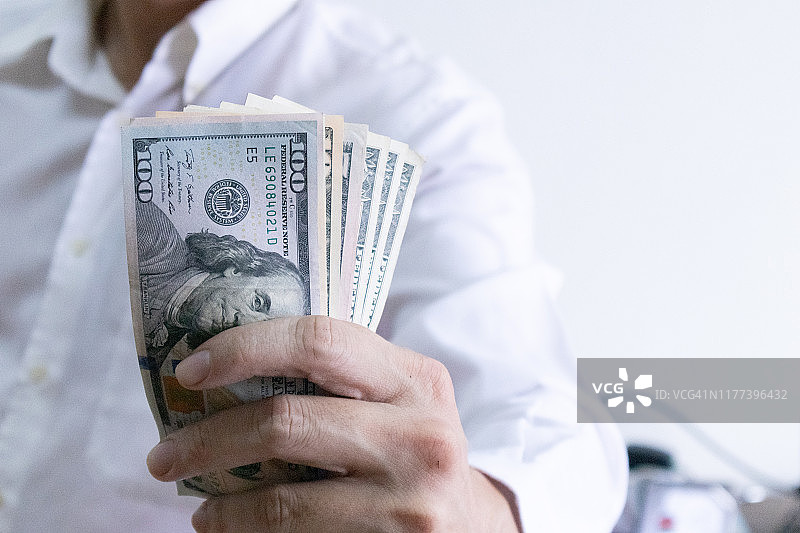 男人拿着美元钞票，年轻商人持有现金，商业和金融赚钱和储蓄概念图片素材