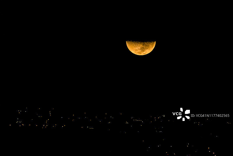 夜晚城市上空的半月图片素材