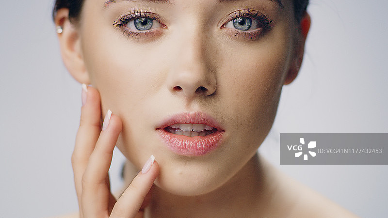 娇羞女性面部肌肤护理，轻触脸庞图片素材