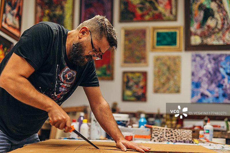 艺术家在他的工作室里用手术刀切割画布图片素材
