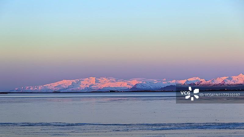 日出时分粉色的雪山和蓝色大海图片素材