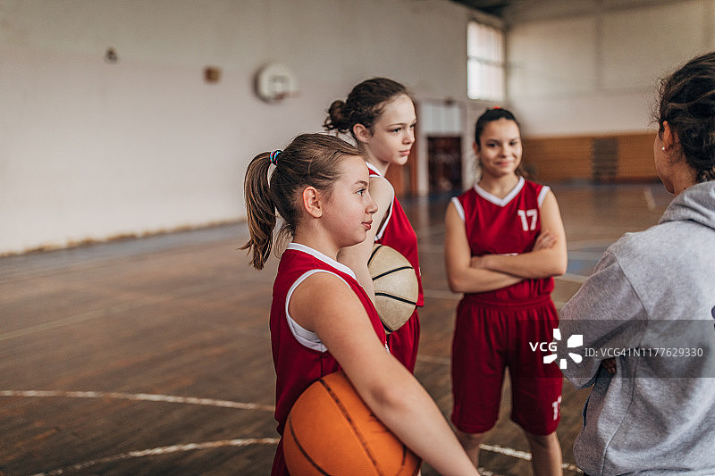 年轻女孩们在暂停时听篮球教练讲解战术图片素材