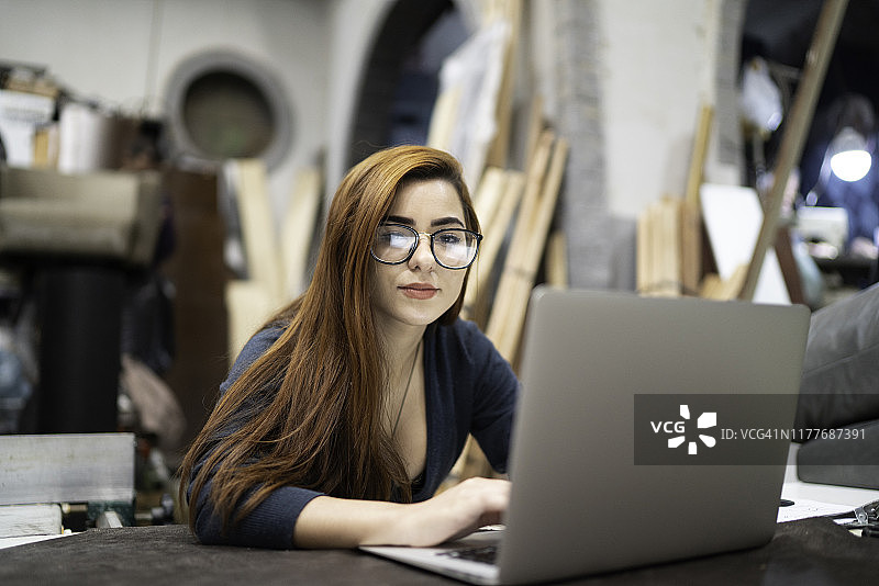 在装潢工坊使用笔记本电脑的年轻女子图片素材