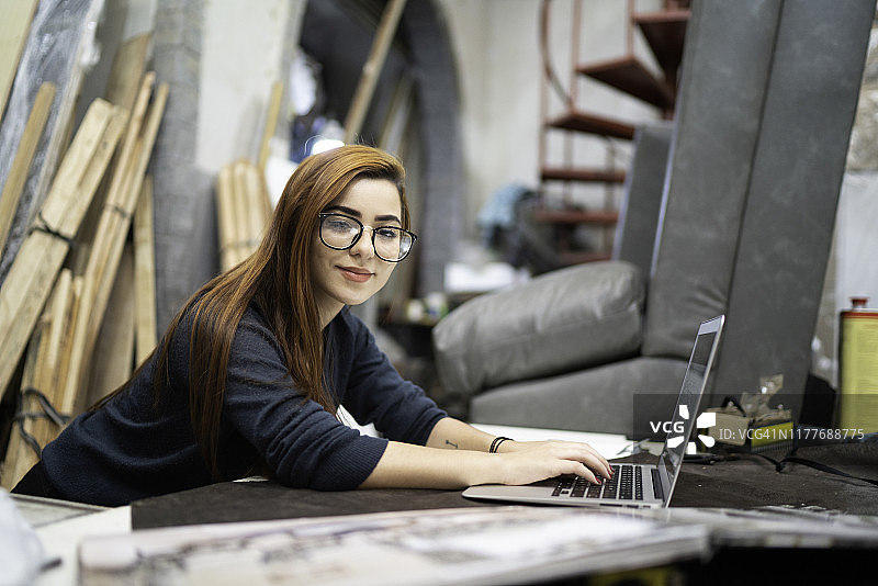 在装潢工坊使用笔记本电脑的年轻女子图片素材