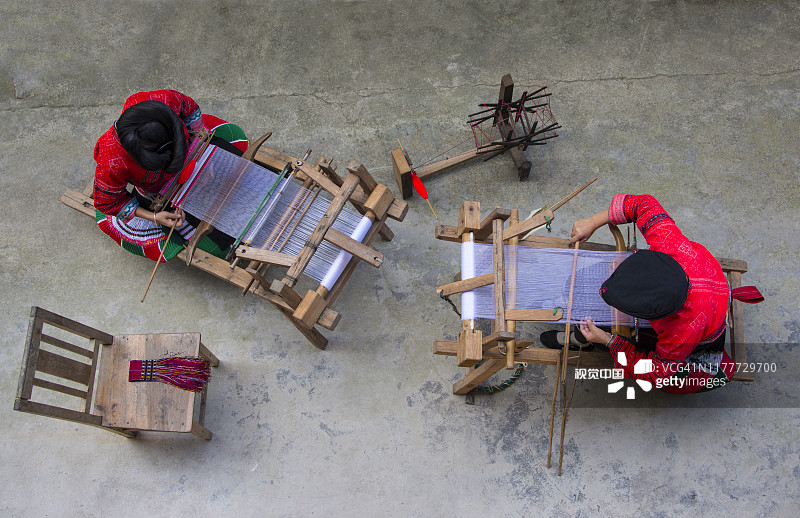 中国龙胜，两位瑶族妇女在木制织布机上纺织图片素材