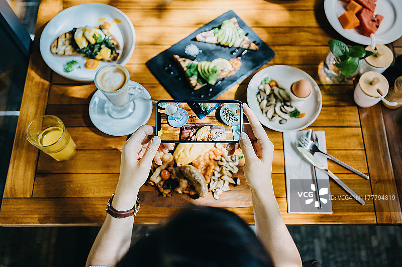 在户外餐厅用智能手机拍摄早午餐照片的女性图片素材