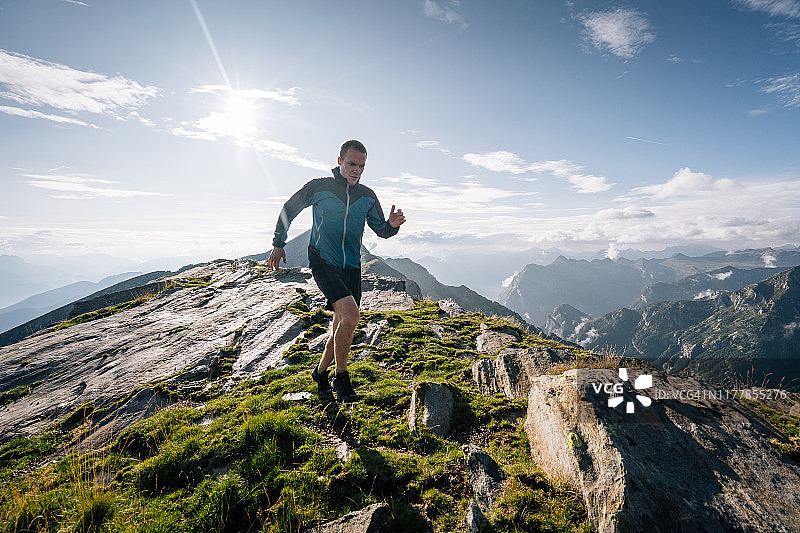 沿着山脊奔跑的跑步者进入光芒中图片素材