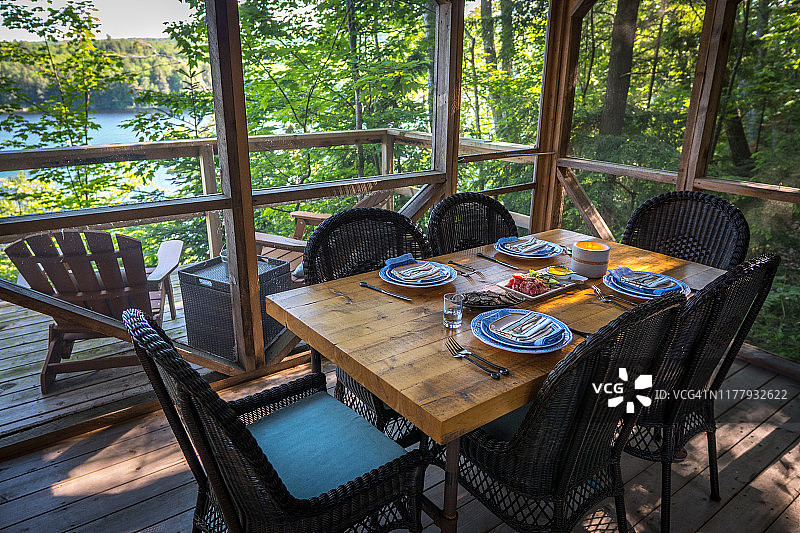 带纱窗的门廊，俯瞰荒野湖泊，餐桌已布置好图片素材