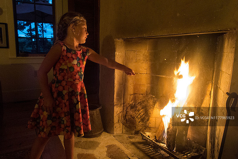 年轻女孩冬日在壁炉旁烤棉花糖图片素材