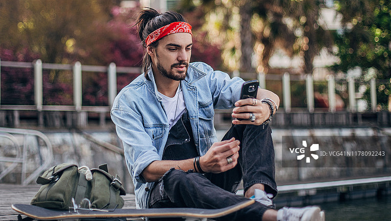 使用手机的年轻潮男滑板爱好者图片素材