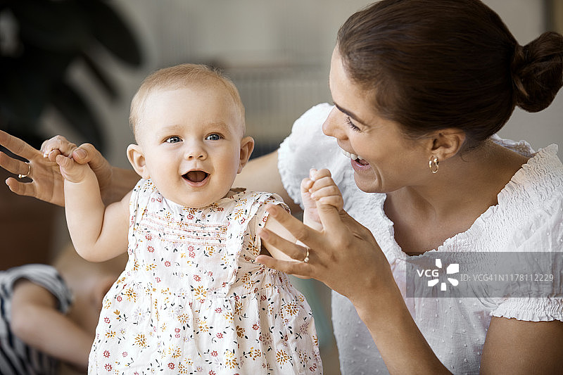 快乐的妈妈牵着可爱女婴的手图片素材