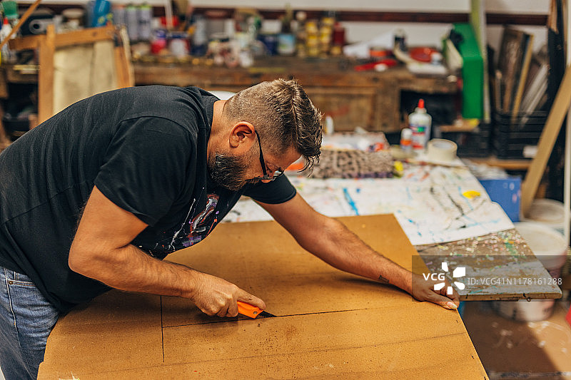 男艺术家切割木板进行绘画图片素材