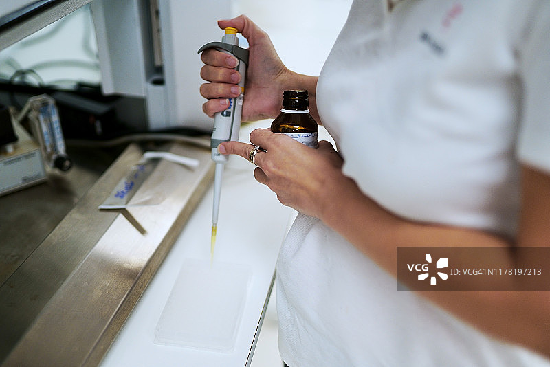 在实验室中用移液管吸取细胞培养基的科学家图片素材