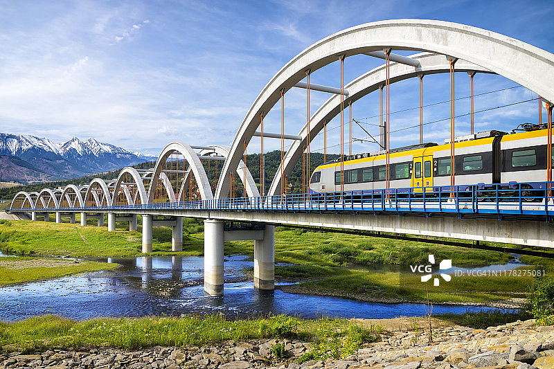 郊区客运列车驶过高架桥，通往塔特拉山脉图片素材