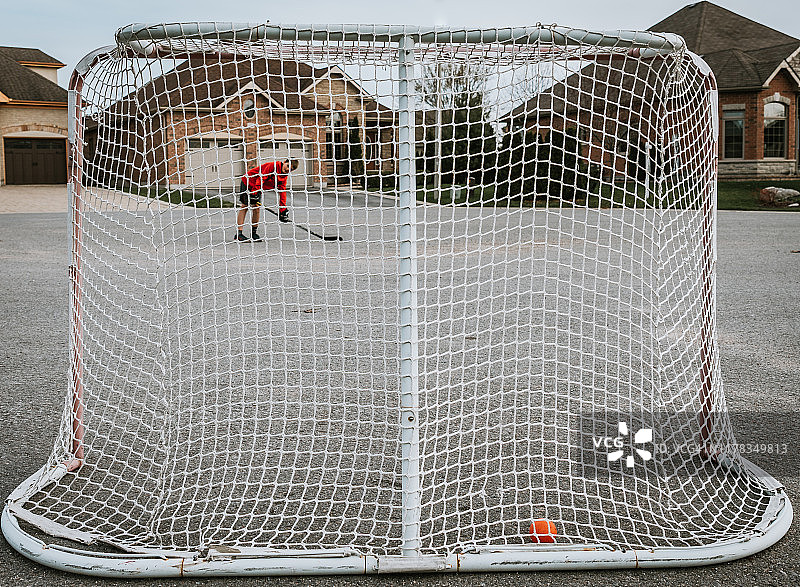 青少年男孩在街上将球射入室外曲棍球网图片素材